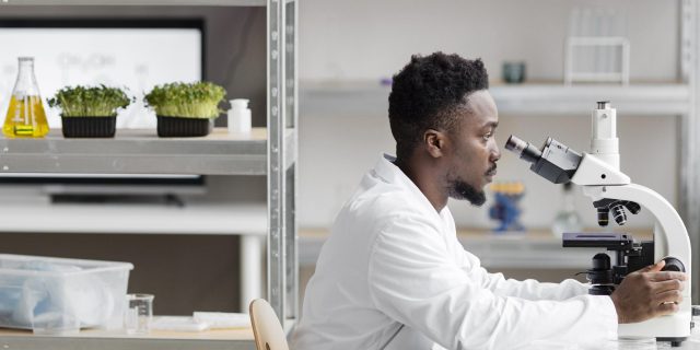 side view male researcher laboratory looking through microscope
